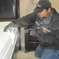 Bed bug inspection technician checking a mattress and bed frame for signs of infestation in Saint Louis, MO