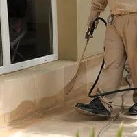 General pest control technician spraying exterior perimeter around a home in Saint Louis, MO
