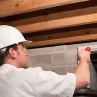 Termite inspection technician checking a basement wall and framing for termite activity in Saint Louis, MO
